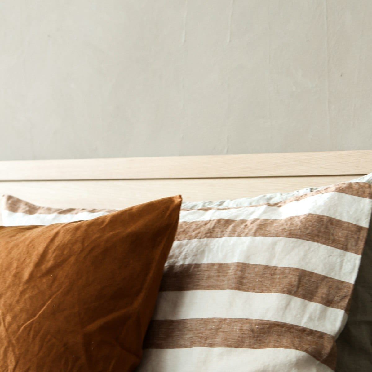 Aproximação nas almofadas de tom caramelo sobre a roupa de cama