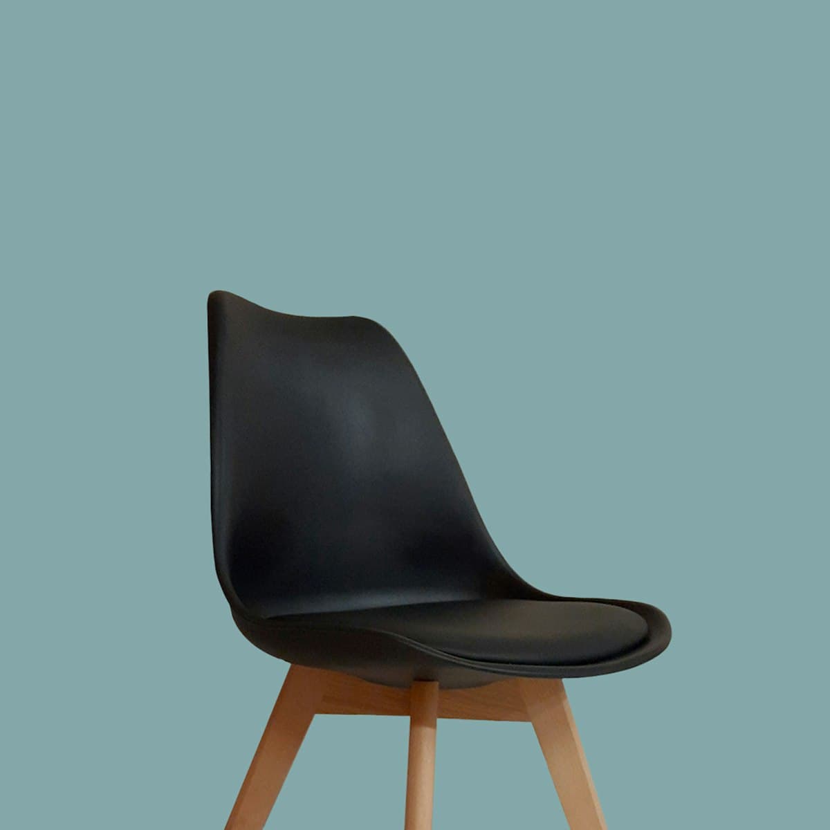 Cadeira Eames preta com base de madeira clara, vista de perfil em fundo colorido