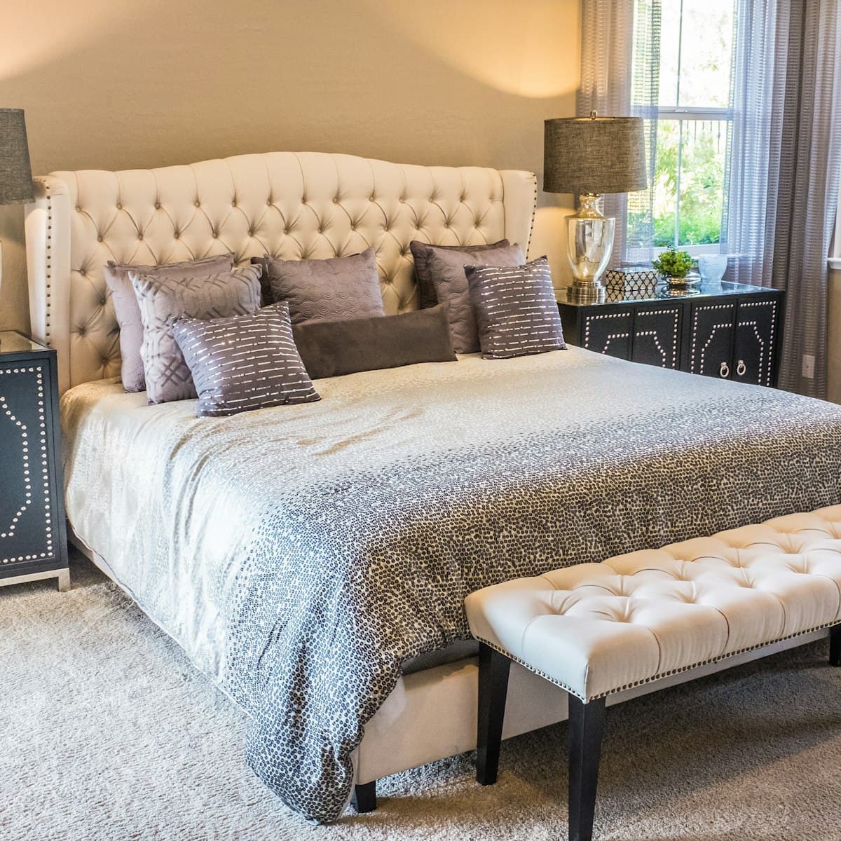 Cama box de casal com cabeceira capitonê bege e roupa de cama clara em quarto amplo